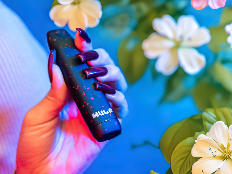 woman holding the Wulf LX Slim with summer flowers and blue background